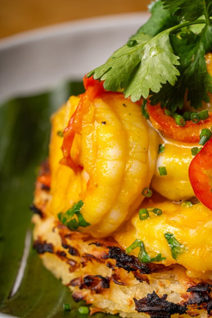 Delicious shrimp dish garnished with fresh cilantro and red peppers, served on a leafy background.