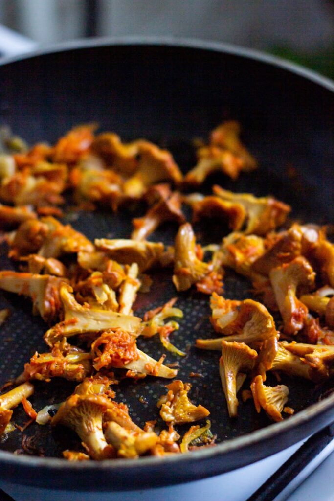 Close-up of sautéed chanterelle mushrooms in a frying pan, rich in earthy flavors.